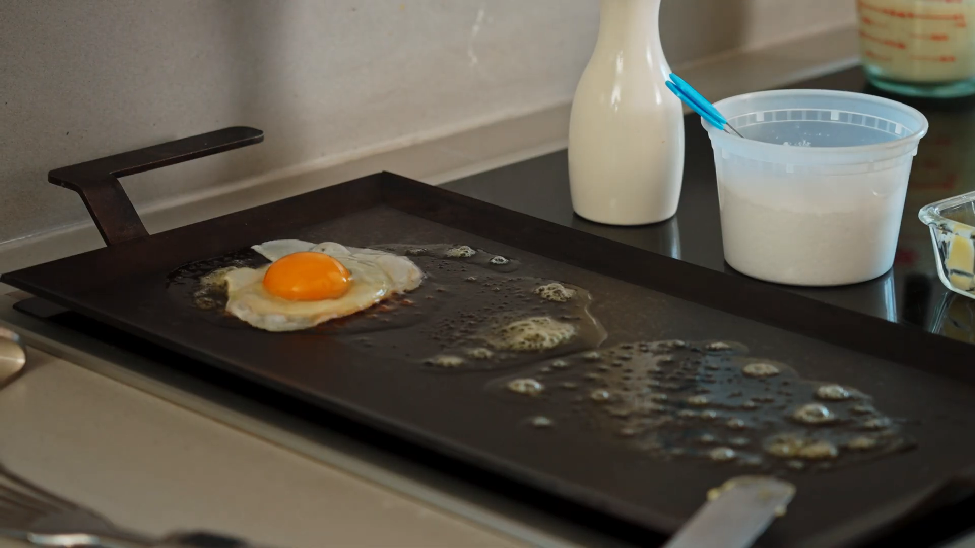 Egg with broken and spread yolk cooking on a griddle