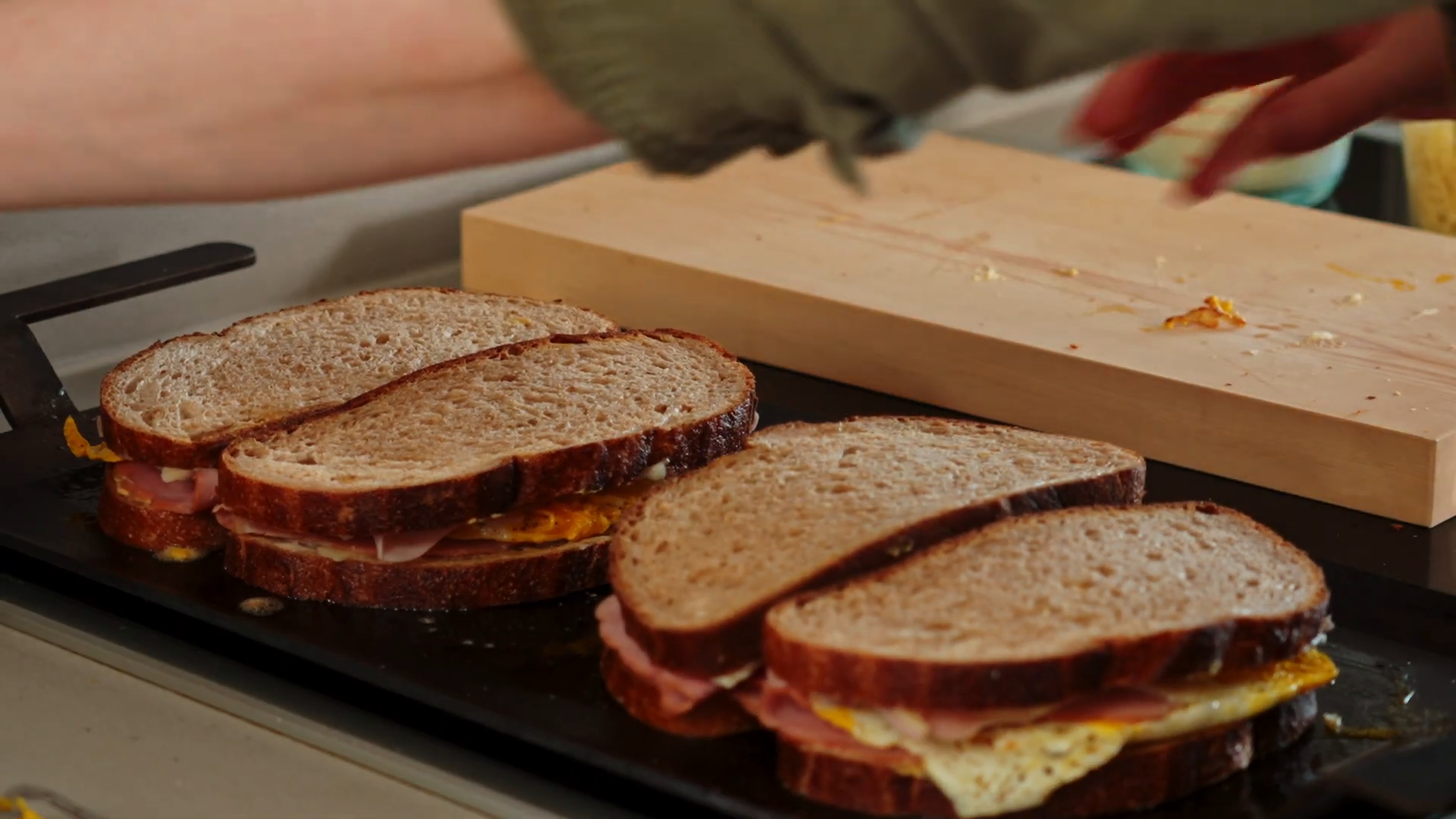Croque madame sandwich being assembled and pressed on a griddle